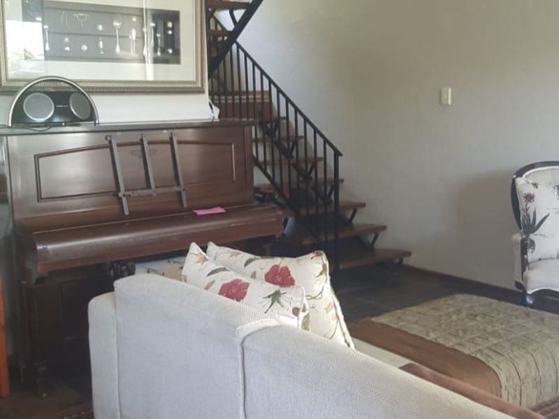 Living room featuring slate tile flooring and an open-tread staircase with a wrought iron balustrade.