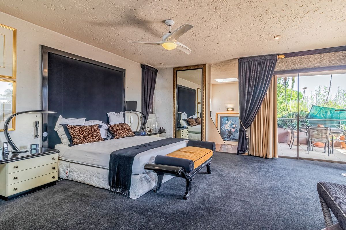 Spacious bedroom featuring a textured ceiling, ceiling fan, and sliding glass doors that open onto a private balcony.