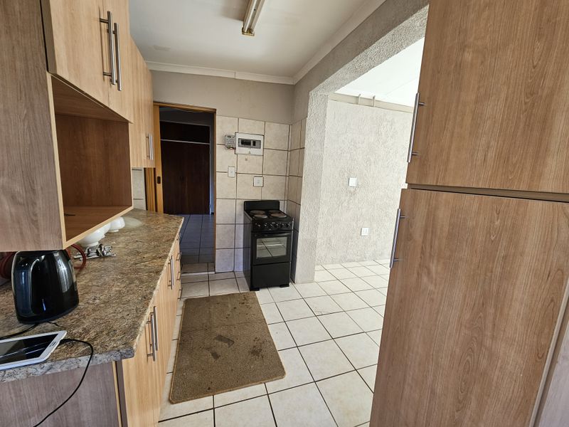 Functional kitchen featuring laminate cabinetry, tiled splashbacks, and a freestanding stove, with direct access to adjacent living areas.