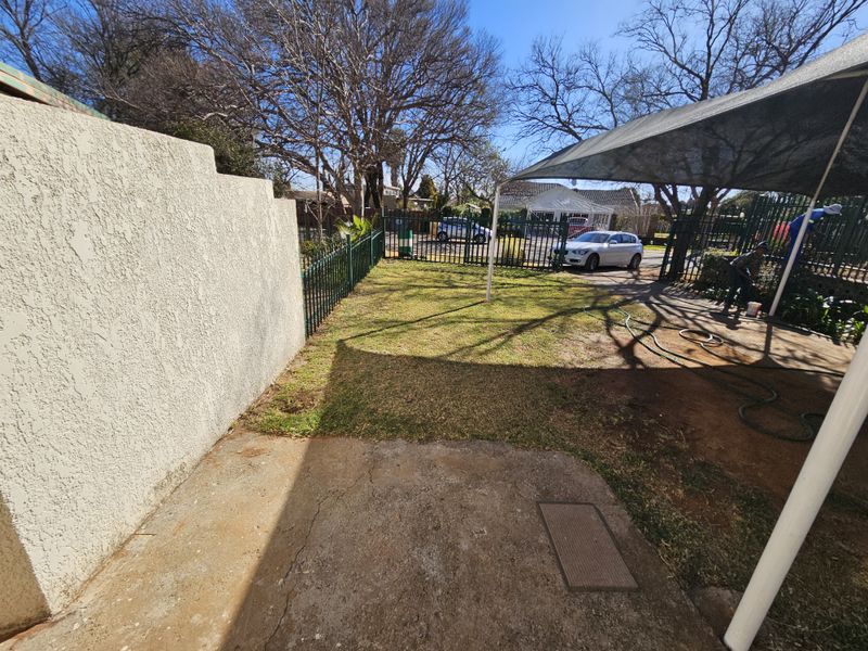 A private rear garden area featuring a concrete patio, shade sail covering, and perimeter fencing, offering potential for landscaping and outdoor living improvements.