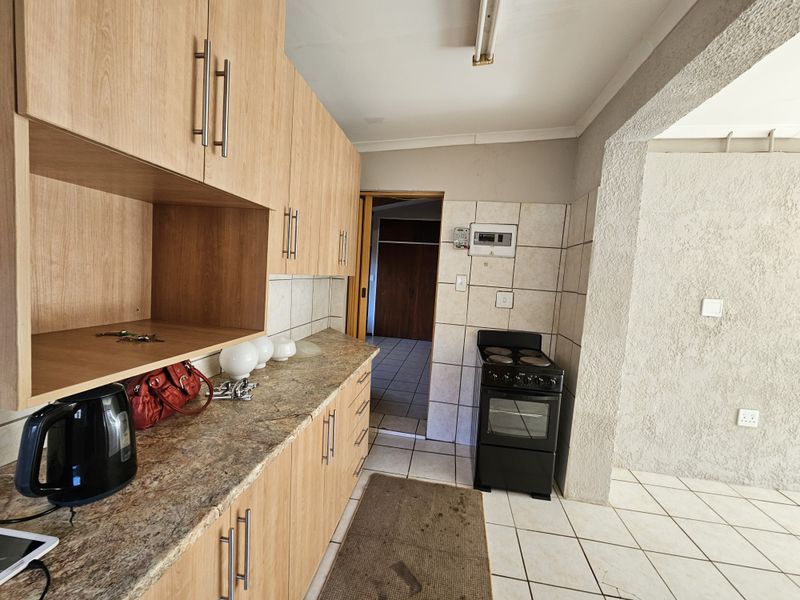 Functional kitchen featuring laminate cabinetry, stone-look countertops, and ceramic floor tiling, offering a practical layout with direct access to adjacent living areas.