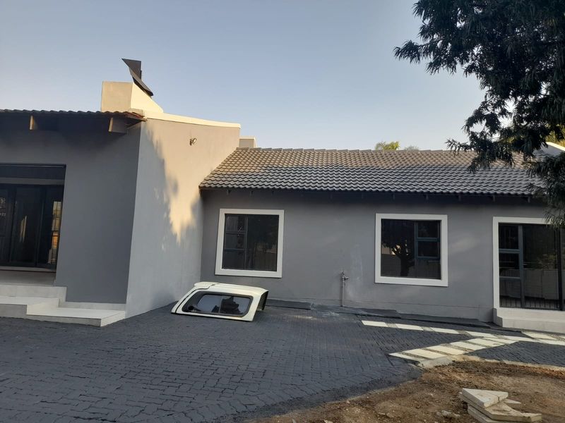 Front exterior view of a modern grey-painted house featuring a tiled roof, paved driveway, and aluminium window frames.