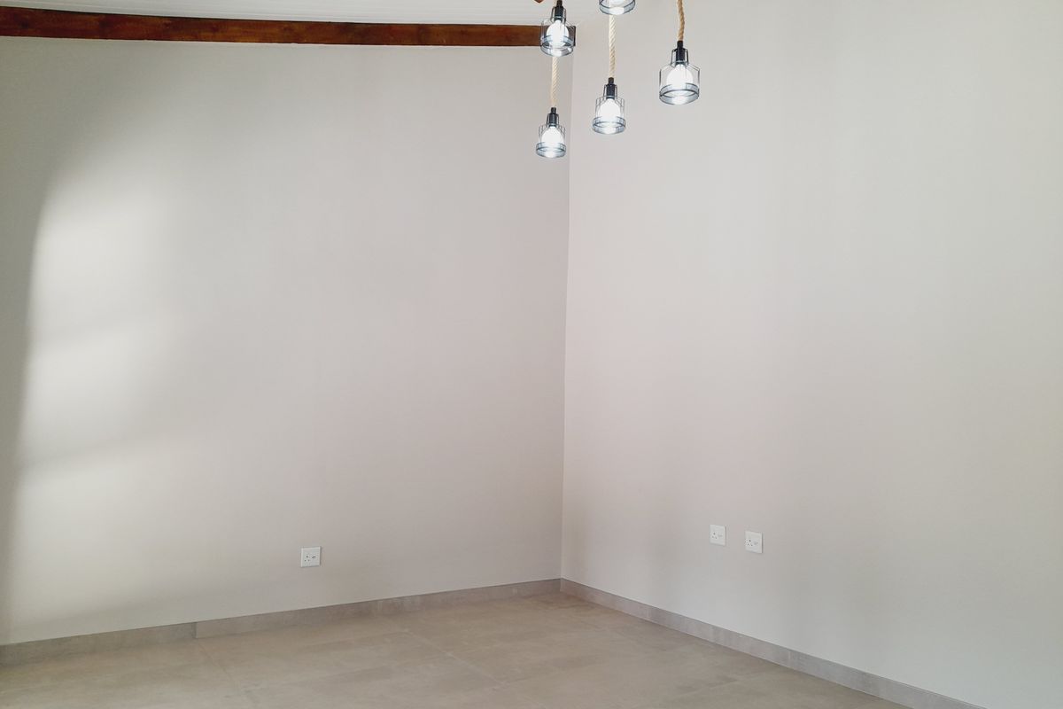 A bright, empty living space featuring neutral tiled floors, exposed timber ceiling beams, and a modern pendant light fixture.