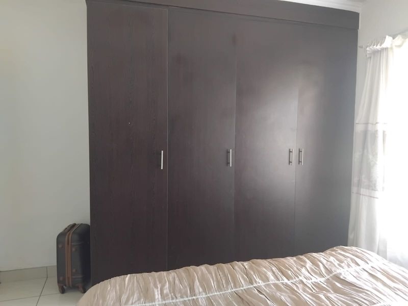 A bedroom featuring a large, dark-toned built-in wardrobe with modern metal handles, providing ample storage space.
