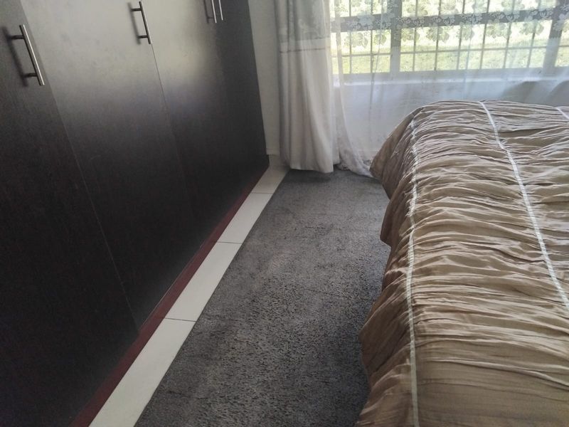 A bedroom featuring dark wood built-in cupboards and tiled flooring, providing functional storage space.