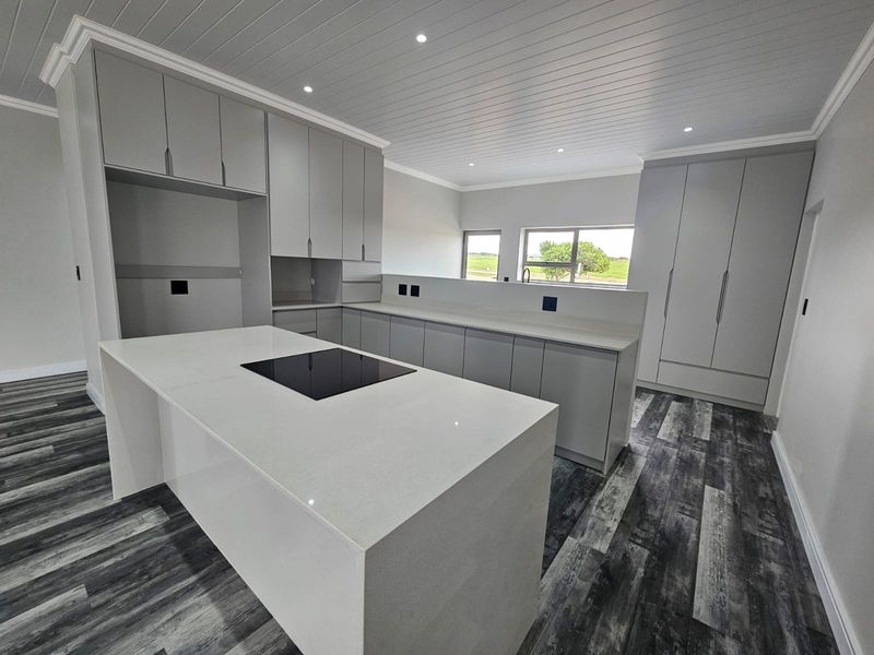 Modern, newly renovated kitchen featuring a central island with an integrated induction hob, ample built-in cabinetry, stone countertops, and stylish laminate flooring.