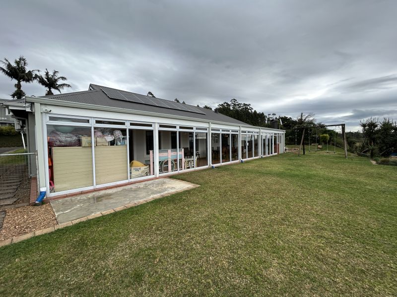 Rear view of the townhouse featuring a large lawn, concrete patio, and extensive sliding glass doors with roof-mounted solar panels.