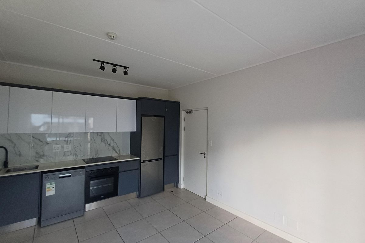 Modern kitchen featuring sleek two-tone cabinetry, marble-look splashback, integrated oven, electric hob, and tiled flooring in a clean, contemporary layout.