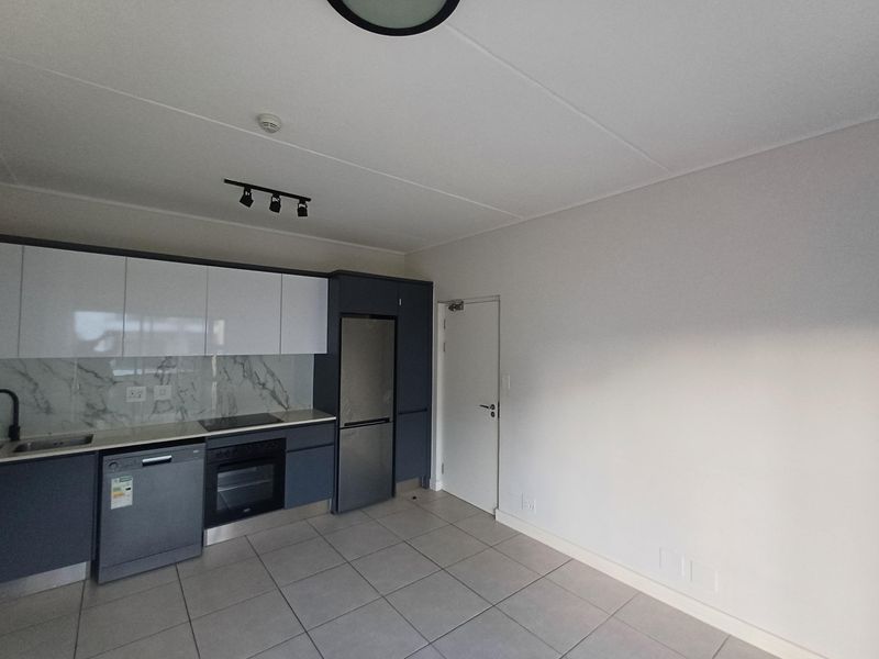Modern kitchen featuring sleek two-tone cabinetry, marble-look splashback, integrated oven, electric hob, and tiled flooring in a clean, contemporary layout.