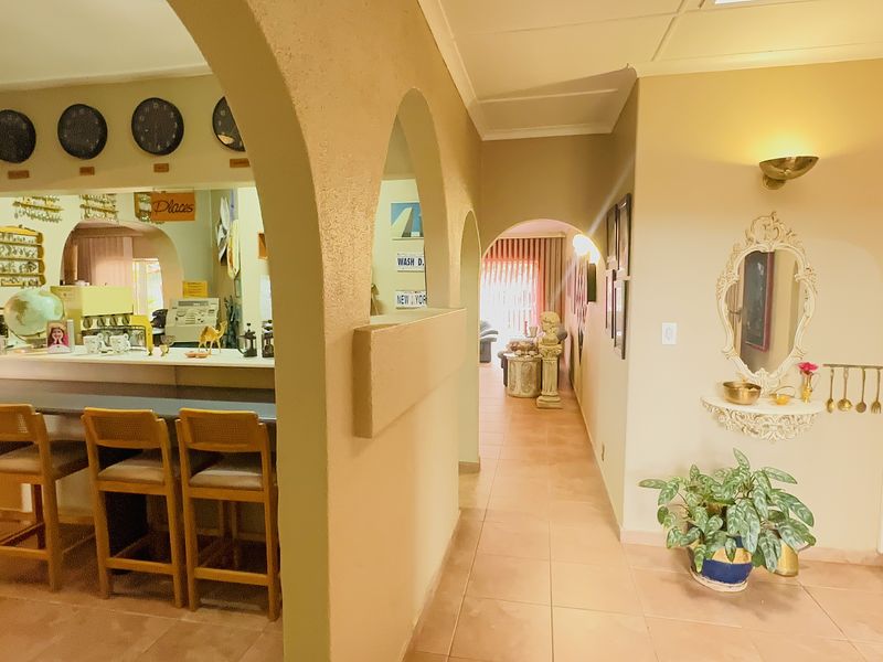 Open plan living area featuring a built-in bar counter, arched architectural details, and tiled flooring throughout the space.