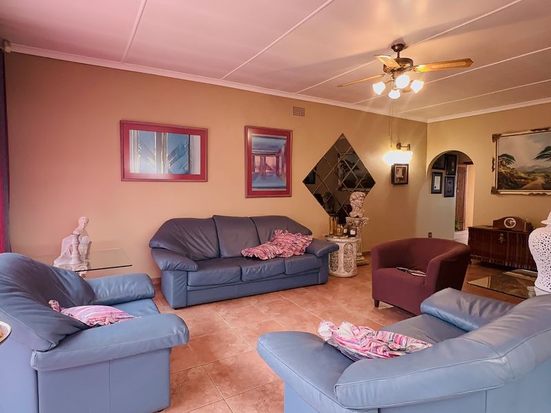 Spacious living room featuring tiled flooring, a ceiling fan, and an arched entryway leading to other parts of the home.