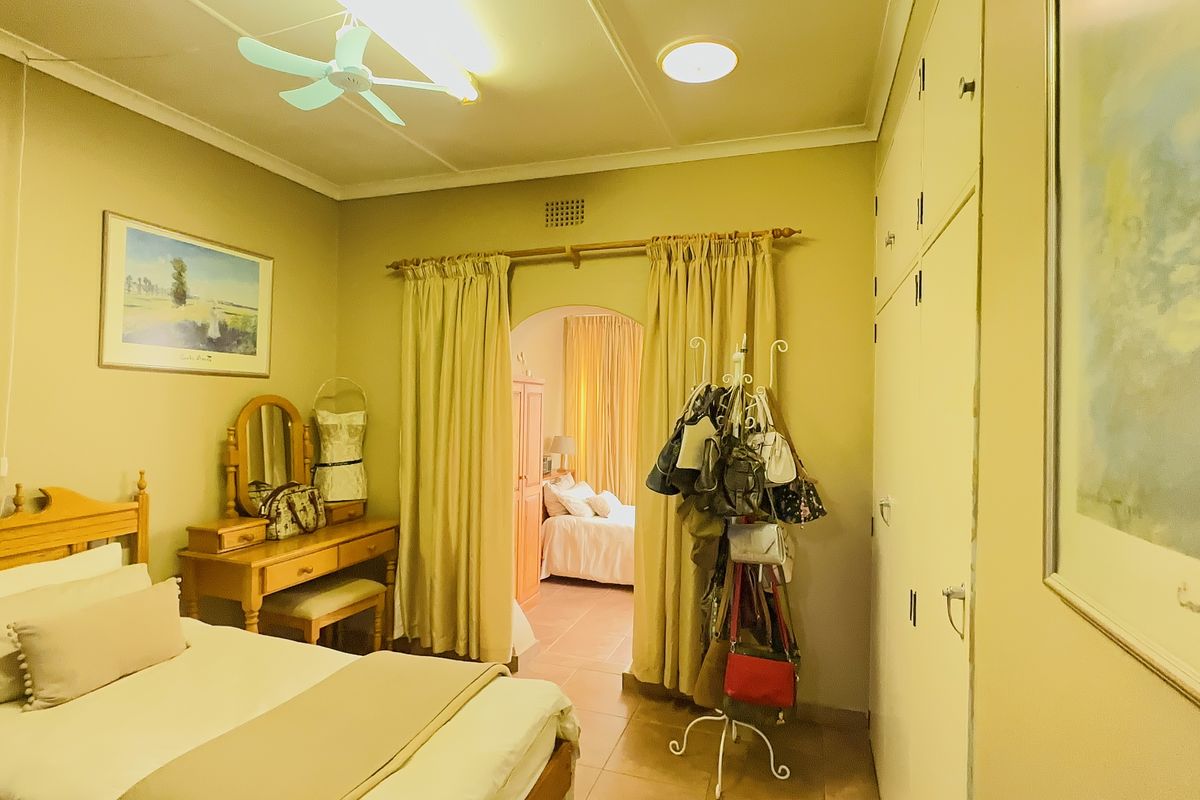 A bedroom featuring built-in cupboards, a ceiling fan, and an arched doorway leading to an adjoining space.