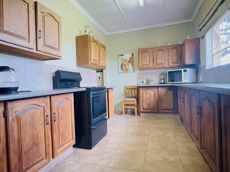 A functional kitchen featuring traditional wooden cabinetry, laminate countertops, tiled flooring, and a freestanding oven, offering a classic layout with ample storage space.