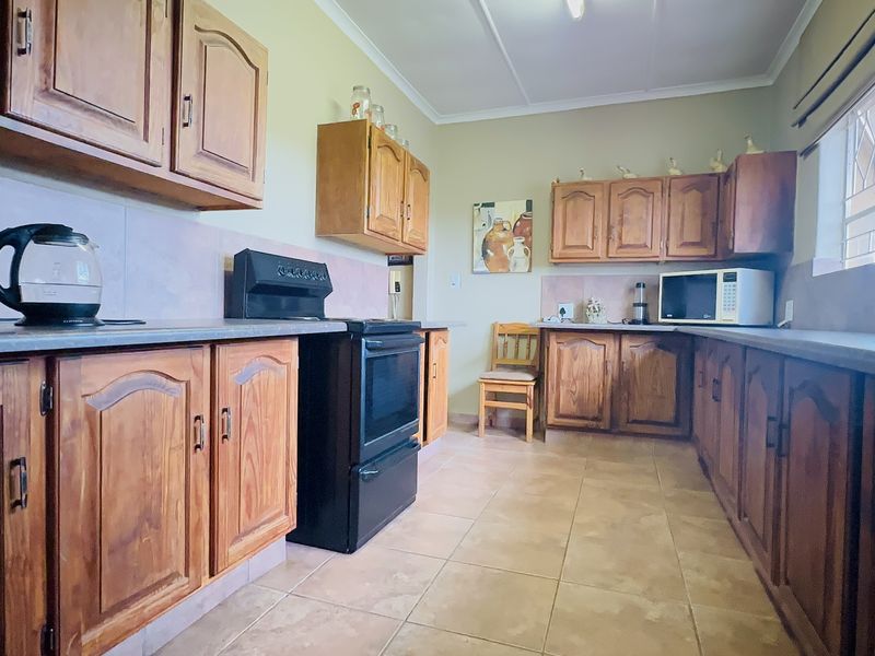A functional kitchen featuring traditional wooden cabinetry, tiled flooring, and a freestanding oven, offering a classic layout with ample storage space.