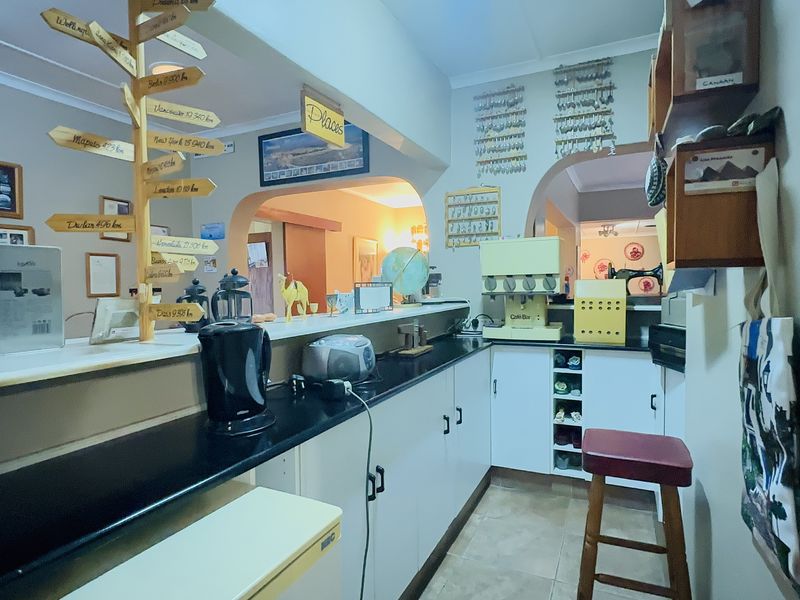 A functional scullery or prep area featuring built-in cabinetry, dark laminate countertops, and tiled flooring, providing additional workspace and storage.