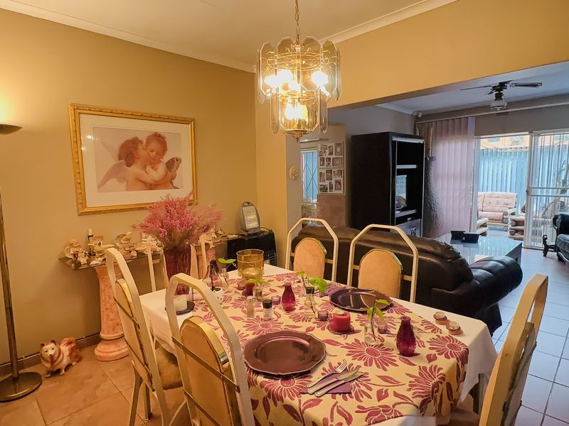 Open-plan dining and living area featuring tiled flooring, a ceiling fan, and direct access to the outdoor patio through sliding glass doors.