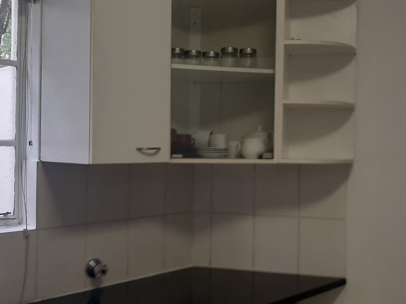 A compact kitchen area featuring white built-in cabinetry, dark countertops, and a tiled backsplash, providing a functional space for food preparation.