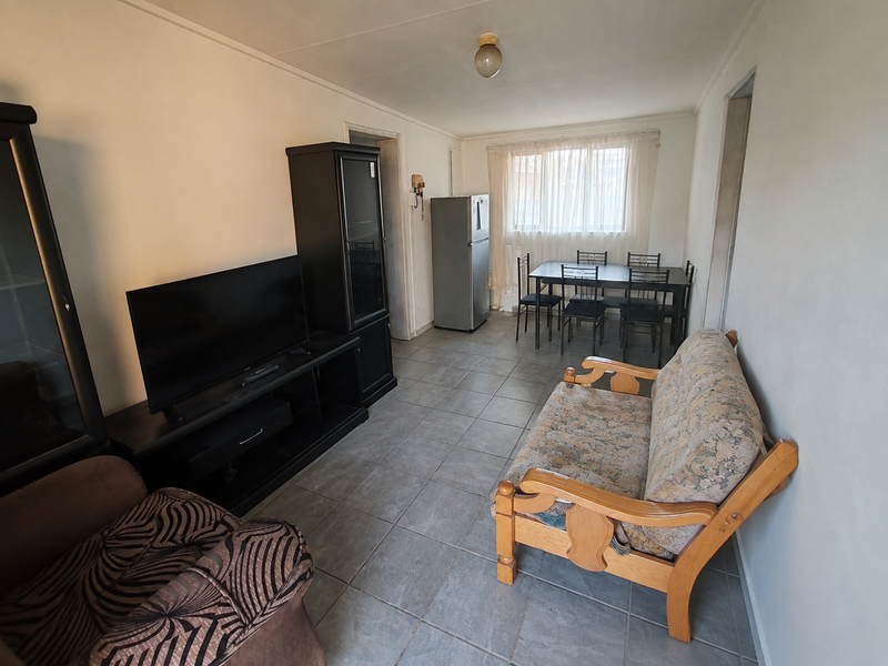 An open-plan living and dining area featuring tiled flooring and neutral walls, providing a functional space for relaxation and meals.