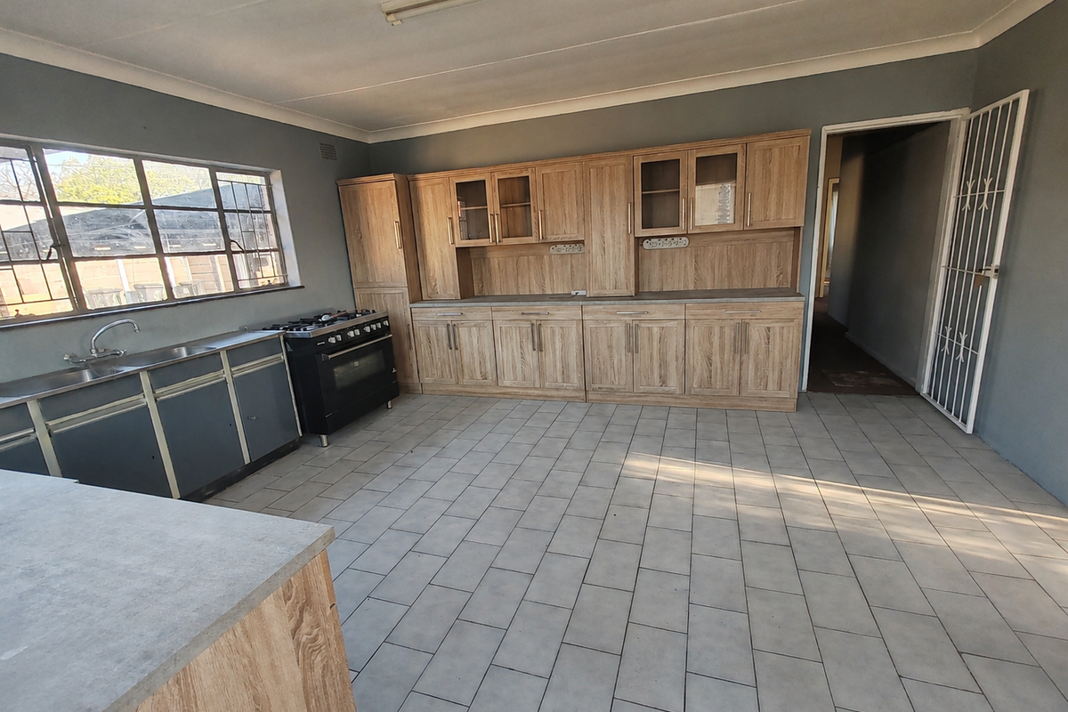 Spacious kitchen featuring a mix of wood-look and metal cabinetry, a gas stove, and tiled flooring, offering a functional layout ready for modernization.