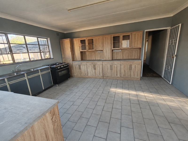 Spacious kitchen featuring a mix of wood-look and metal cabinetry, a gas stove, and tiled flooring, offering a functional layout ready for modernization.