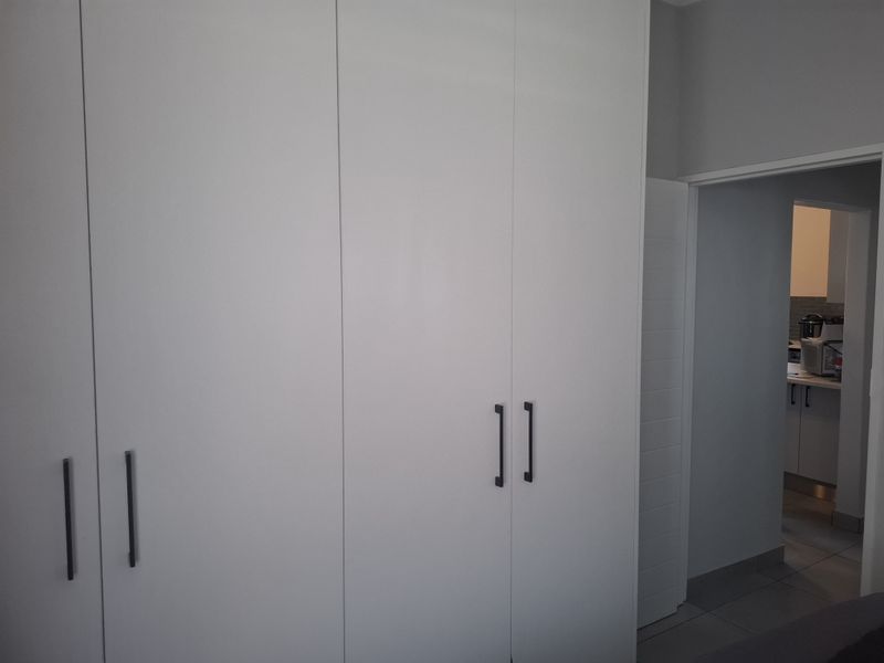A bedroom featuring modern, floor-to-ceiling built-in cupboards with sleek handles, offering ample storage space.