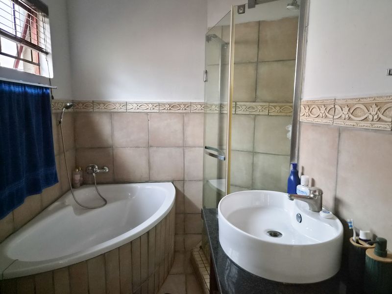 A functional bathroom featuring a corner bathtub, a separate glass-enclosed shower, and a modern vessel sink set on a granite vanity countertop.