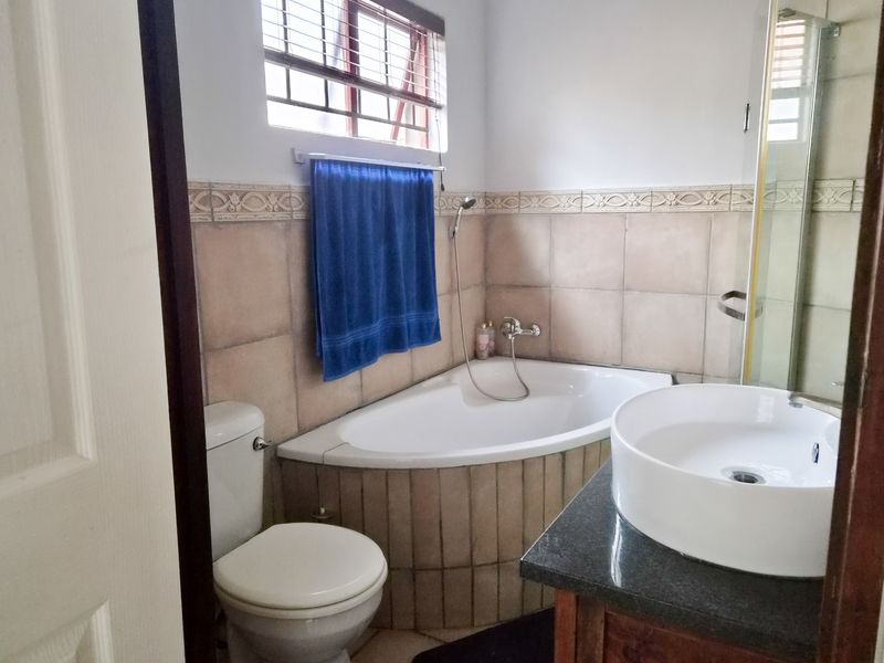 A functional bathroom featuring a corner bathtub, a modern vessel sink on a granite vanity, and a separate shower enclosure.