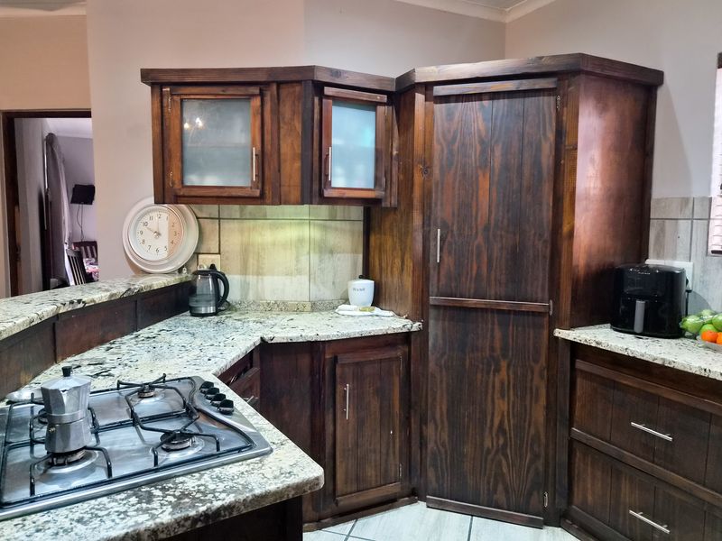 A kitchen featuring dark wood cabinetry, granite countertops, and a built-in gas hob with a tiled backsplash.