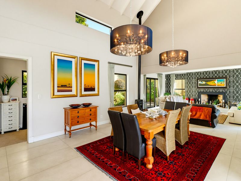 Spacious open-plan living and dining area featuring a vaulted ceiling, tiled floors, a freestanding fireplace, and large sliding doors leading to the outdoors.