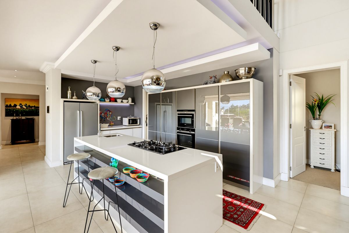 Modern kitchen featuring a central island with a gas hob, integrated appliances, sleek cabinetry, and a stylish drop ceiling with recessed lighting.