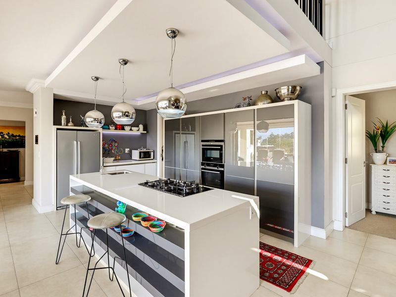 Modern kitchen featuring a central island with a gas hob, integrated appliances, sleek cabinetry, and a stylish drop ceiling with recessed lighting.