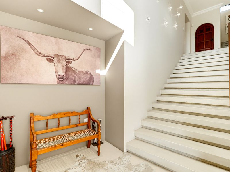 A bright and welcoming entrance hall featuring a prominent staircase and an elegant arched doorway leading to the upper level.