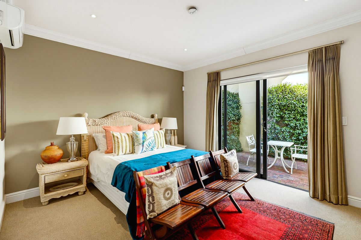 Spacious bedroom featuring neutral tones, recessed lighting, and a sliding glass door providing direct access to a private paved patio area.