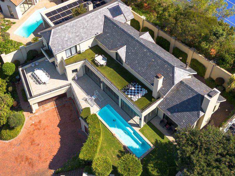 Aerial view of a luxury residence featuring a swimming pool, expansive terrace, solar panels, and well-maintained landscaped grounds.