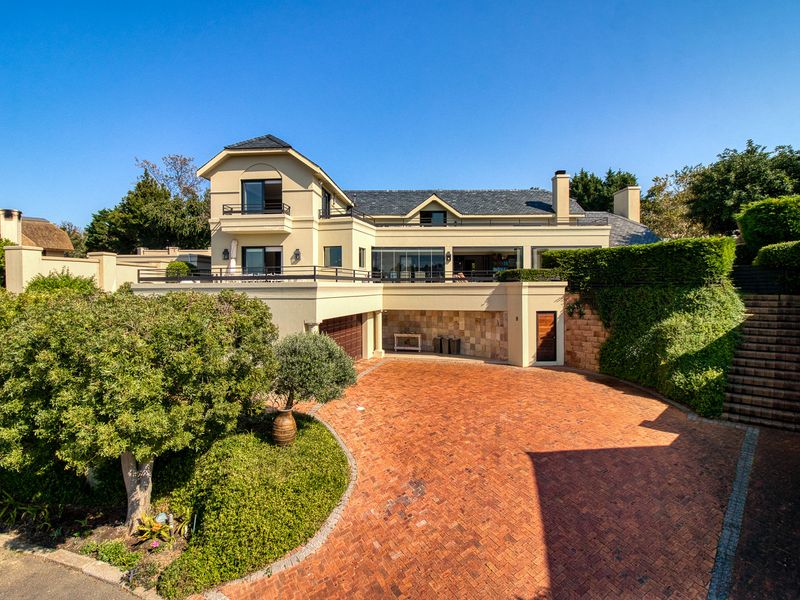 A well-maintained multi-level residence featuring a spacious brick-paved driveway, integrated garage, and elevated balcony areas with stone accents.
