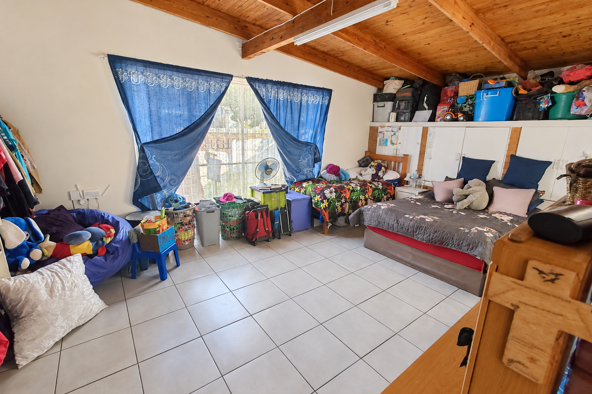Spacious bedroom featuring exposed timber ceiling beams, tiled flooring, and built-in storage cupboards.