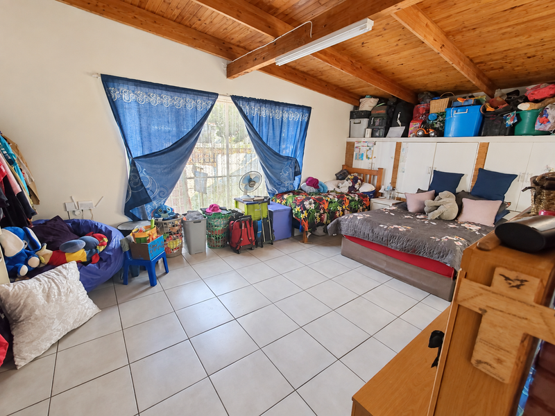 Spacious bedroom featuring exposed timber ceiling beams, tiled flooring, and built-in storage cupboards.