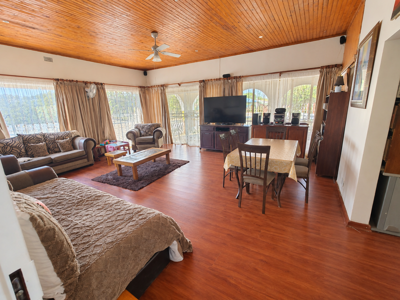 Spacious open-plan living and dining area featuring warm timber ceilings, laminate flooring, and large sliding glass doors providing ample natural light.