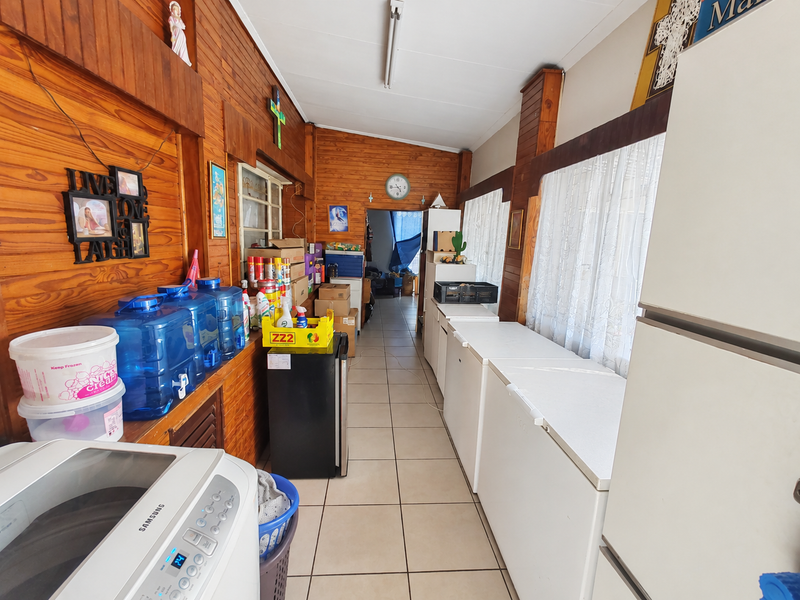 A functional laundry and utility area featuring tiled flooring and timber wall paneling, currently utilized for storage and appliance housing.