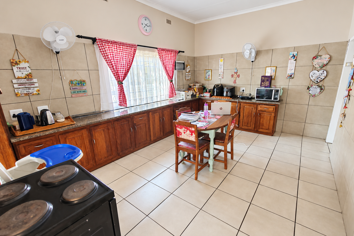 Spacious kitchen featuring extensive wooden cabinetry, granite countertops, and neutral tiled flooring, offering a functional layout with ample storage and preparation space.