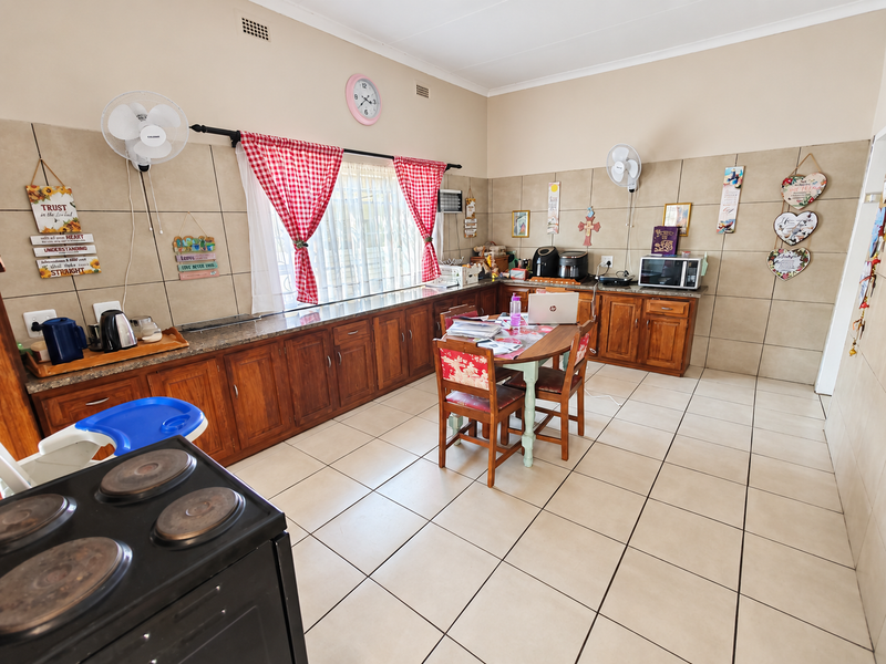 Spacious kitchen featuring extensive wooden cabinetry, granite countertops, and neutral tiled flooring, offering a functional layout with ample storage and preparation space.