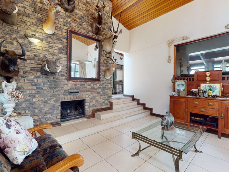 Spacious living room featuring an exposed brick feature wall with a built-in fireplace, tiled flooring, and a high timber-clad ceiling.
