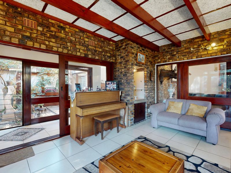 Spacious living room featuring exposed brick walls, timber ceiling beams, and large sliding glass doors providing access to the outdoor area.