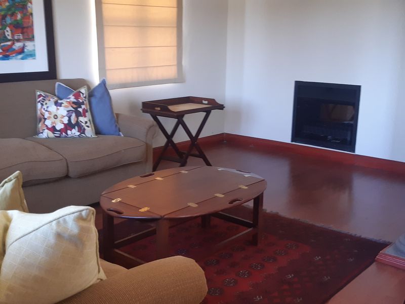 A comfortable living room featuring warm hardwood flooring, a built-in fireplace, and a structural column, creating a cozy and inviting atmosphere.