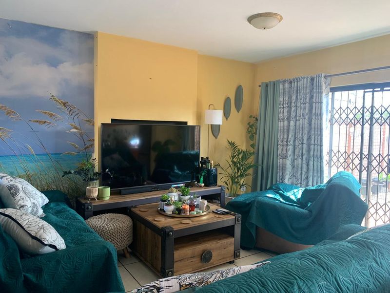 A comfortable living room featuring tiled flooring and a sliding glass door with a security gate, providing access to the outdoor area.