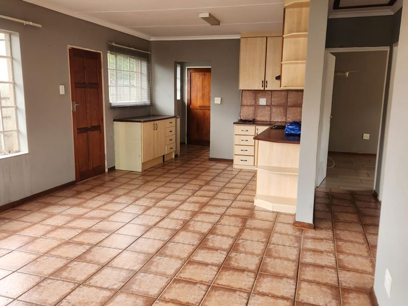 Open plan living and kitchen area featuring tiled flooring, built-in cabinetry, and neutral wall tones, offering a functional space ready for modernization.