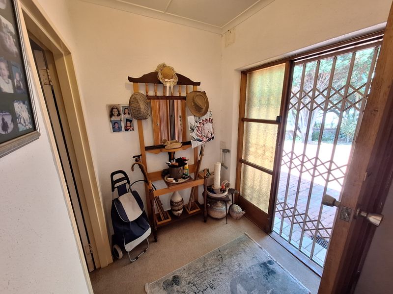 A functional entry area featuring a security gate, timber door frame, and carpeted flooring, providing access to the home's interior.