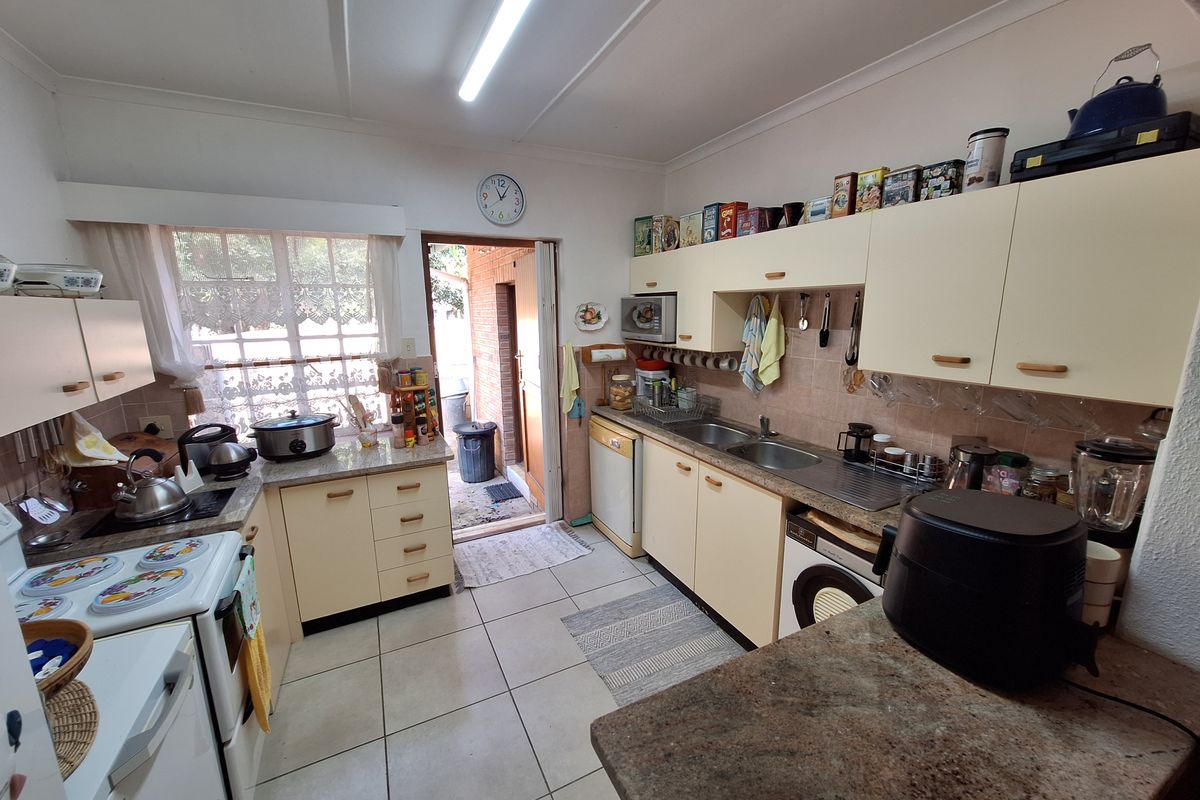 Functional kitchen featuring built-in cabinetry, stone countertops, double sink, and tiled flooring with direct access to the exterior.