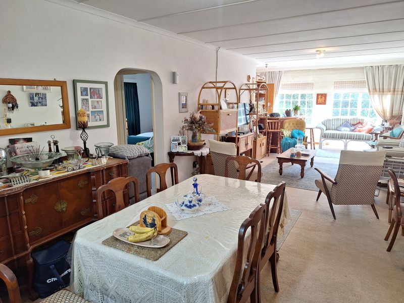 Spacious open-plan living and dining area featuring an arched doorway, large windows for natural light, and neutral carpeting throughout.