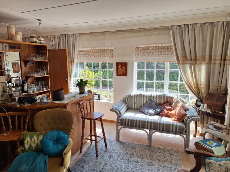 A cozy living room featuring a built-in wooden bar area and large lattice windows that provide natural light and garden views.